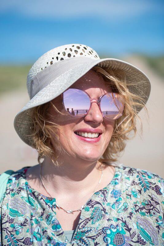 vrouw met glimlach, zonnebril en hoed op